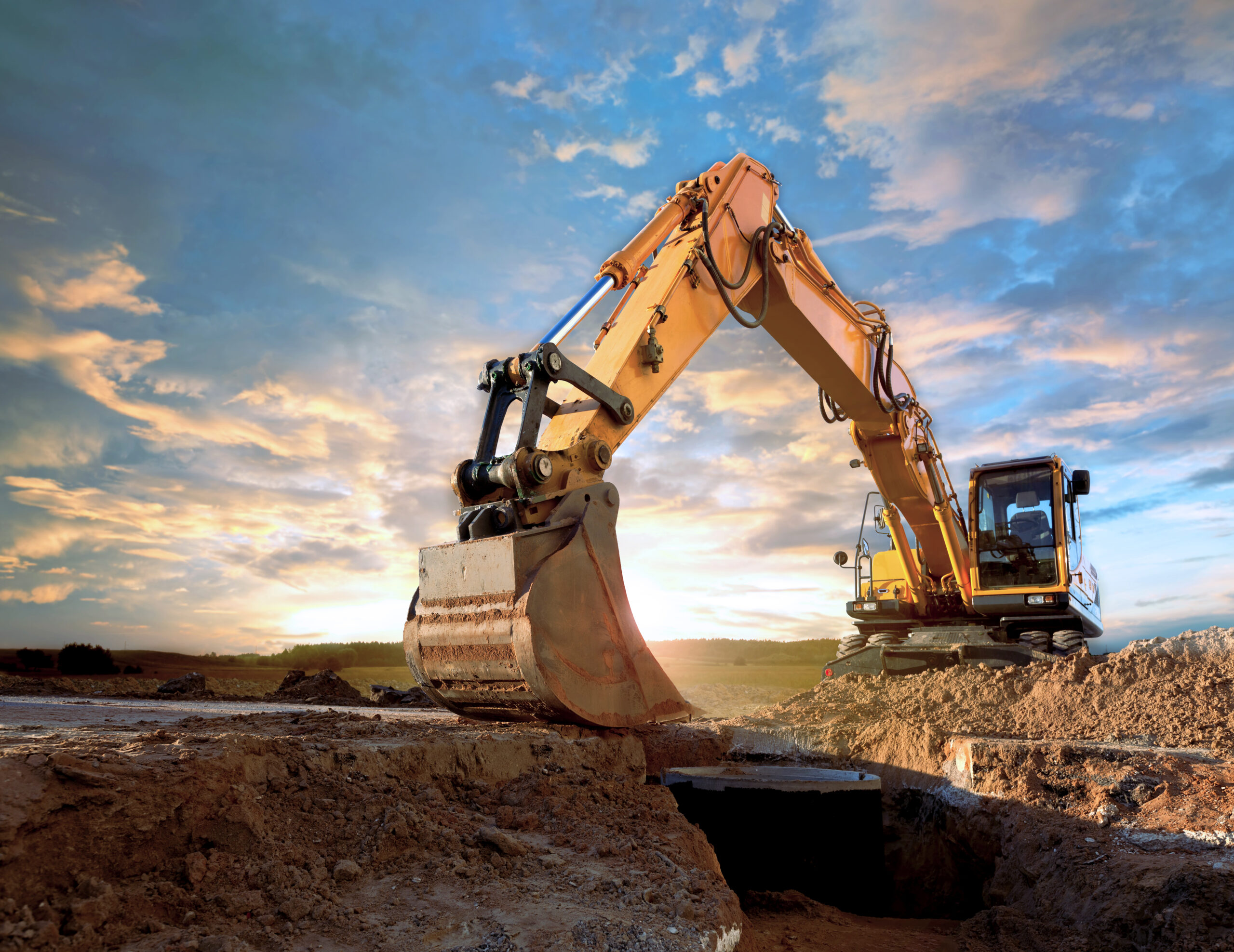 Excavator At A Construction Site Against The Setting Sun.