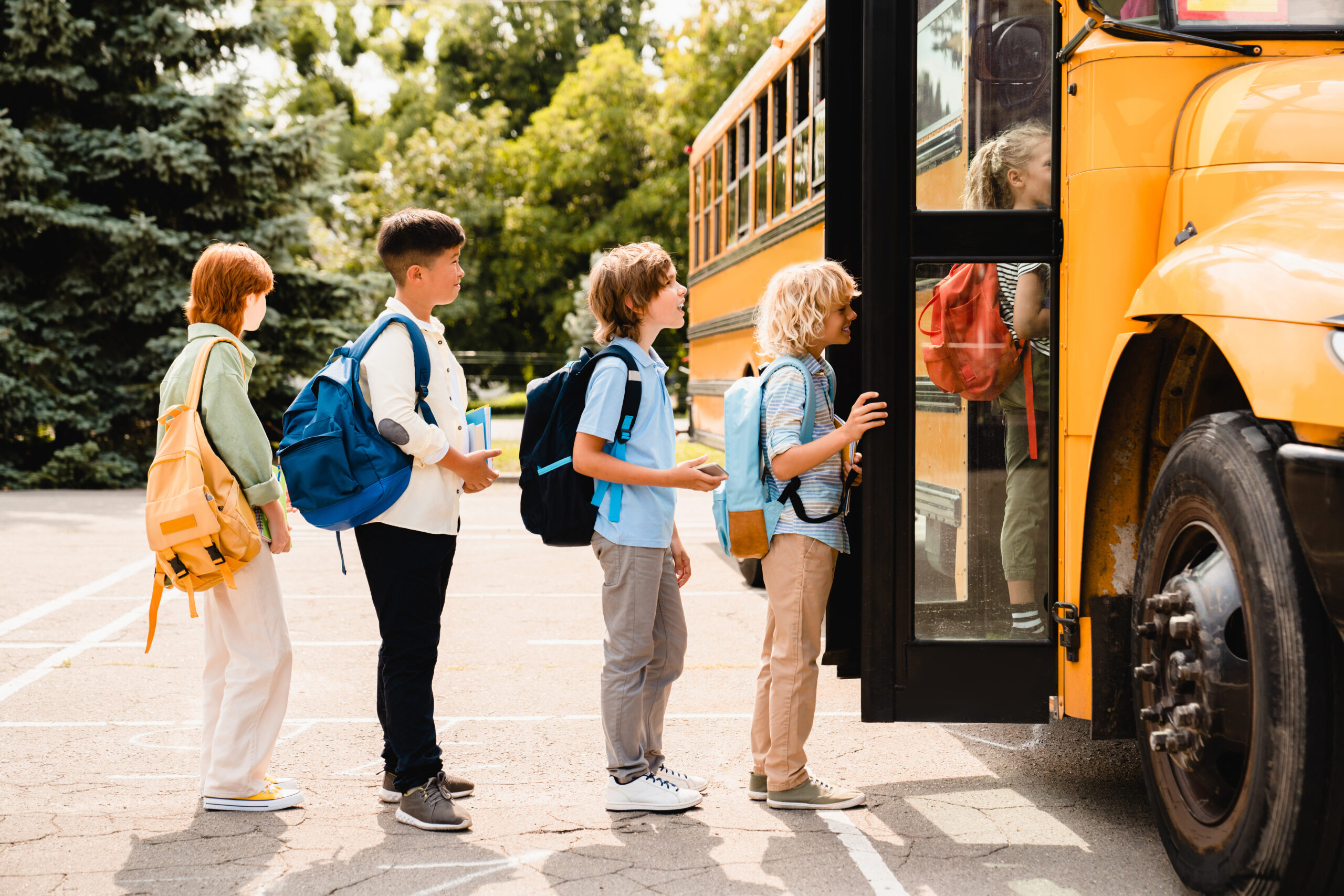 Multiethnic Mixed Race Pupils Classmates Schoolchildren Students Standing In Line Waiting For Boarding School Bus Before Starting New Educational Semester Year After Summer Holidays